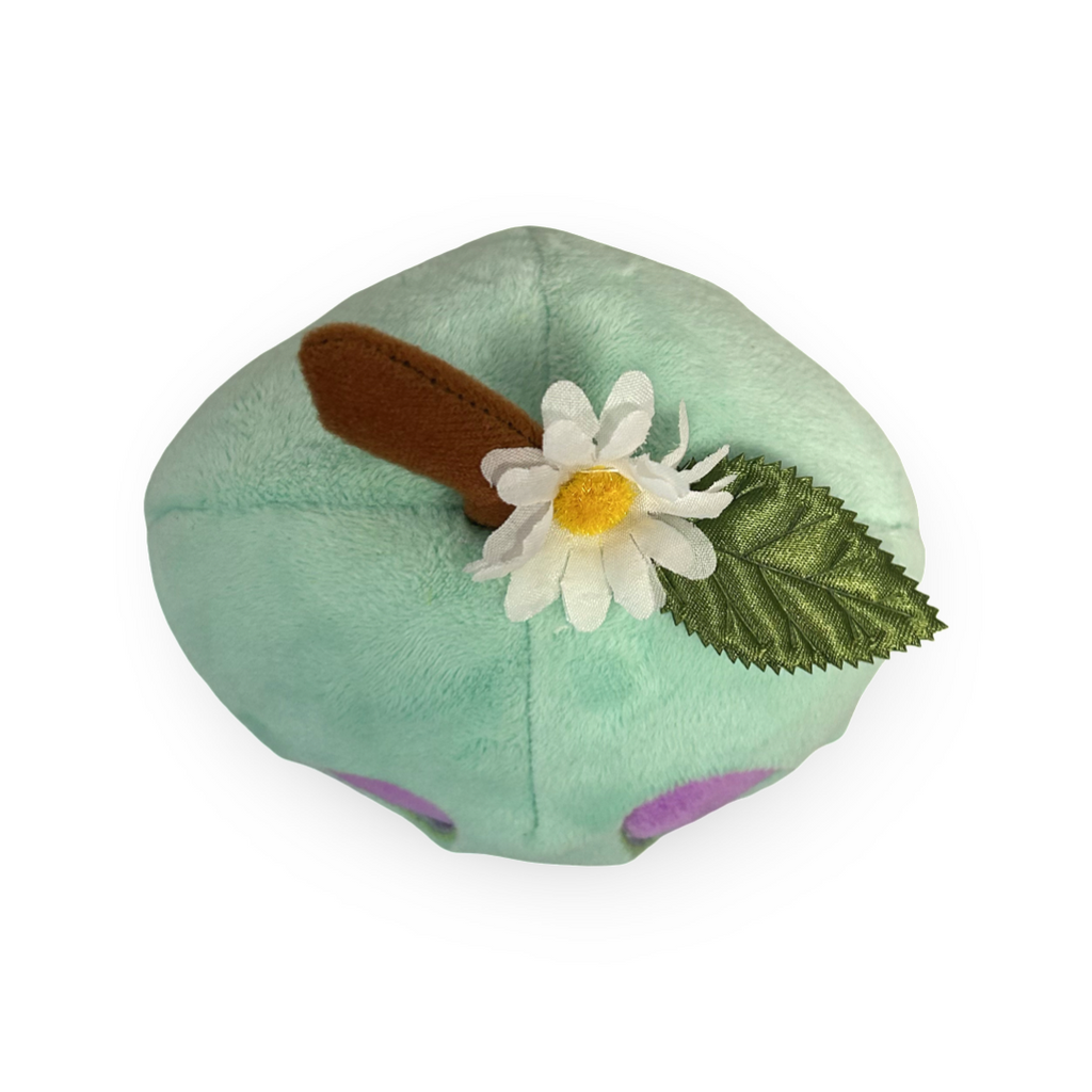 Green plush toy with a flower and leaf on a white background