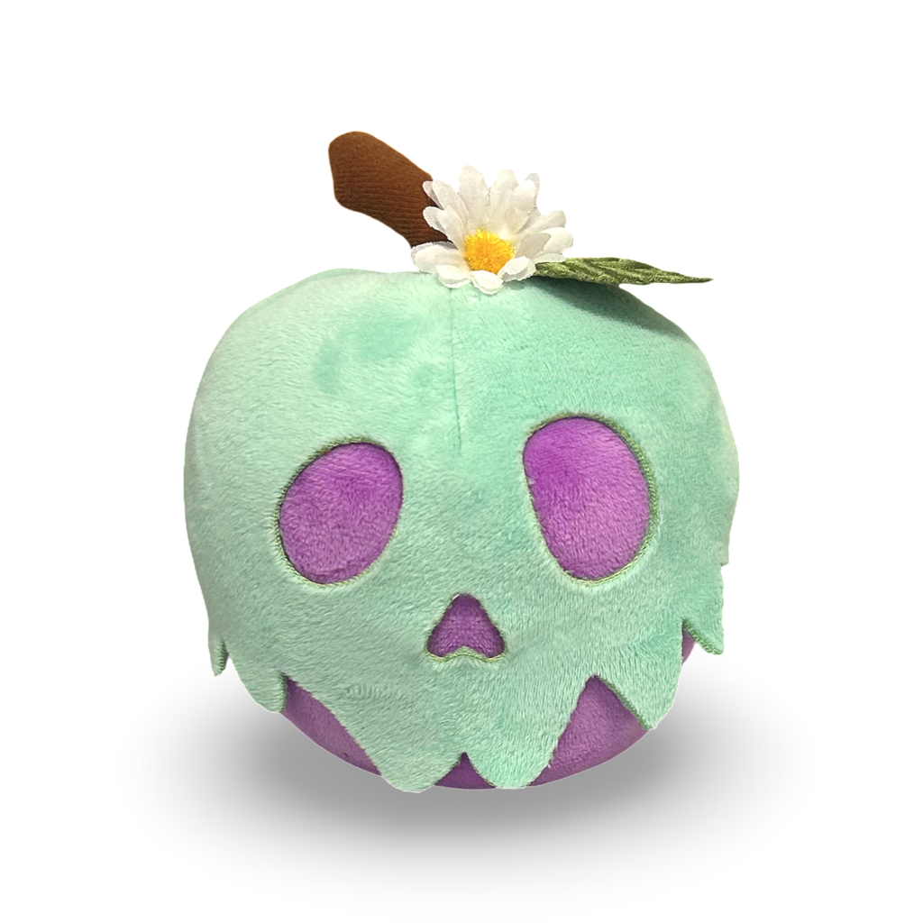 Plush toy shaped like a green apple with a skull design and a flower on top, on a white background.