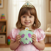 Young girl in a pink dress with a tiara holding a plush toy in a room.