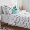 Bed with geometric patterned bedding, teal pillow, and books on a nightstand.