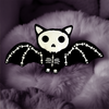 a plush bat laying on fur fabric. plush skeleton bat in black minky fabric with white skeleton embroidery