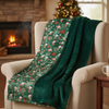 Green floral-patterned blanket draped over a beige armchair in a cozy living room with a fireplace and Christmas tree.
