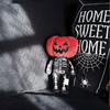 plush pumpkin-head skeleton sitting on a black couch 